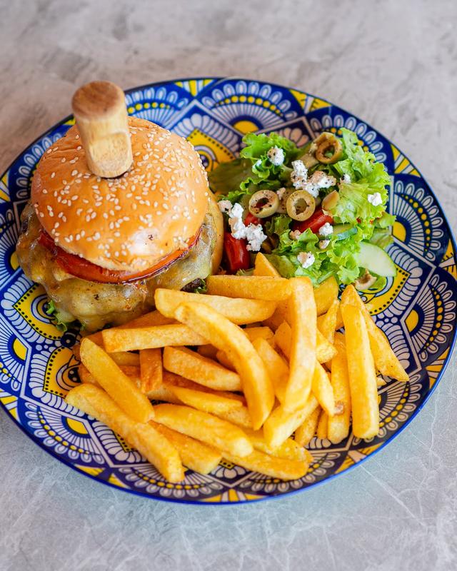 A burger and chips served on a hand painted plate